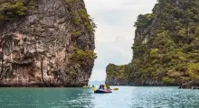 Kayakers explore the turquoise waters surrounded by dense cliffs in Phuket, Thailand.