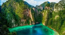 Stunning aerial view of lush green cliffs surrounding turquoise waters in Phuket, Thailand.