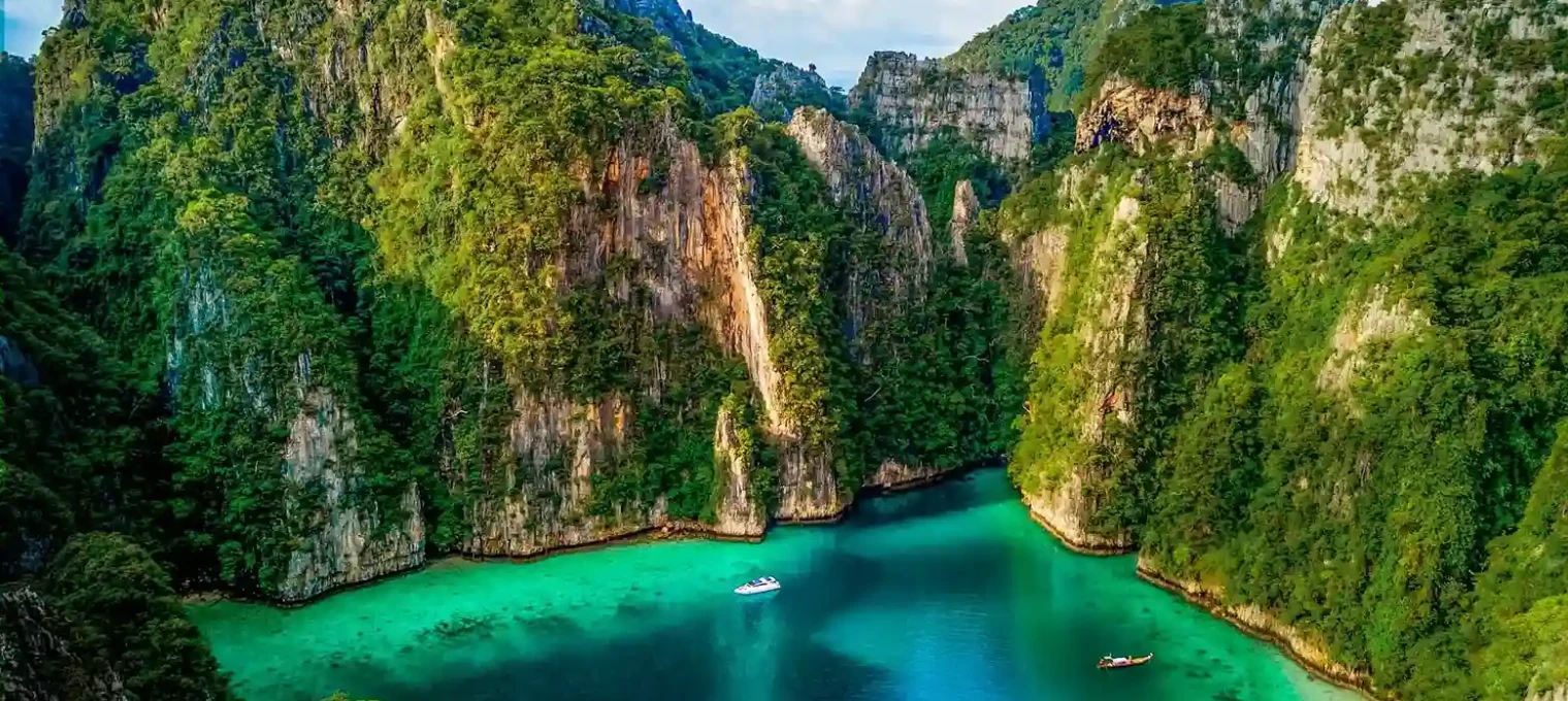 Stunning aerial view of lush green cliffs surrounding turquoise waters in Phuket, Thailand.