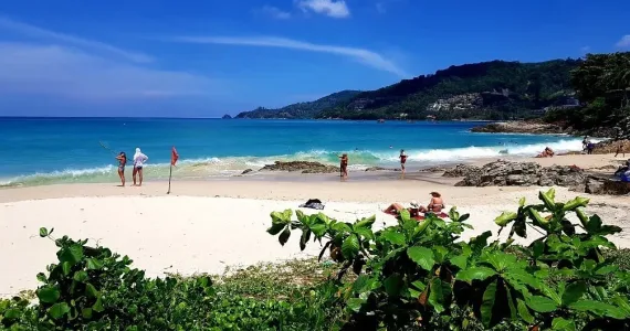 Пляж на Пхукете с белым песком и голубым морем, люди отдыхают и ловят рыбу.