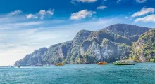 Stunning view of boats near rocky cliffs and turquoise waters in Phuket, Thailand.