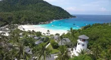 Aerial view of a lighthouse on a beach in Phuket with turquoise waters and lush greenery.