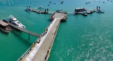 Pier with boats docked in clear turquoise waters of Phuket, Thailand.