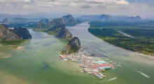 Aerial view of a floating village in Phuket, surrounded by lush mountains and water.