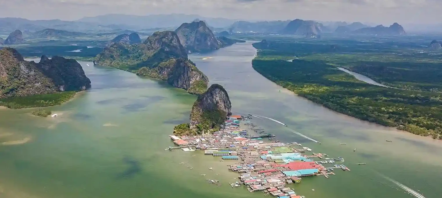 Aerial view of a floating village in Phuket, surrounded by lush mountains and water.