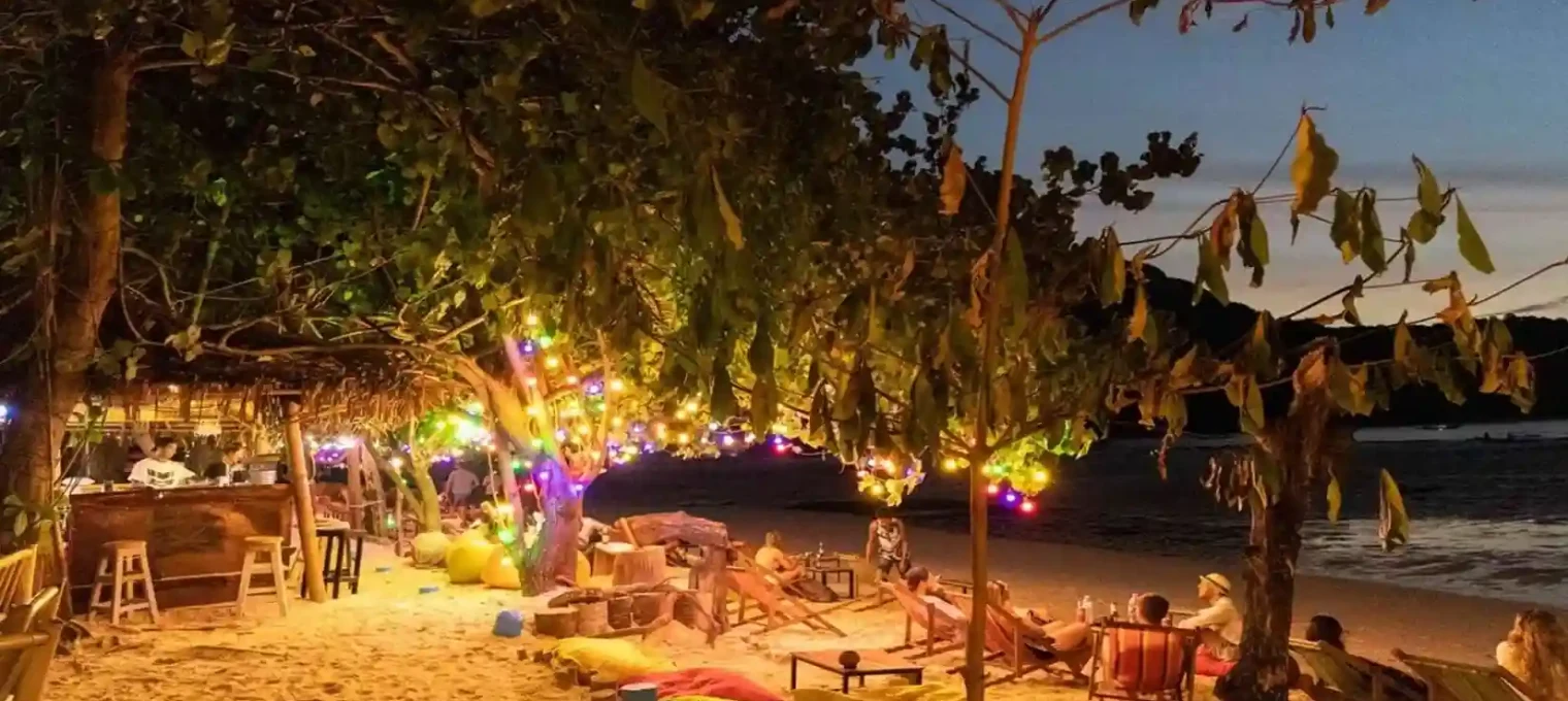 Beachside lounge area in Phuket, adorned with colorful lights at dusk.