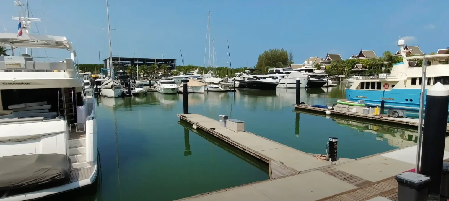 Luxury yachts docked in a serene marina in Phuket, Thailand, on a clear day.
