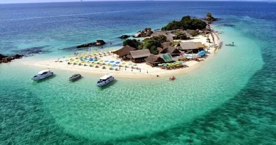 Aerial view of a tropical island in Phuket with clear blue water and beach umbrellas.