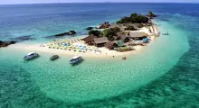 Aerial view of a tropical island in Phuket with clear blue water and beach umbrellas.