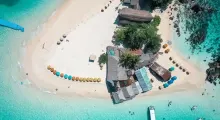 Aerial view of a tranquil beach in Phuket with colorful umbrellas and clear blue waters.