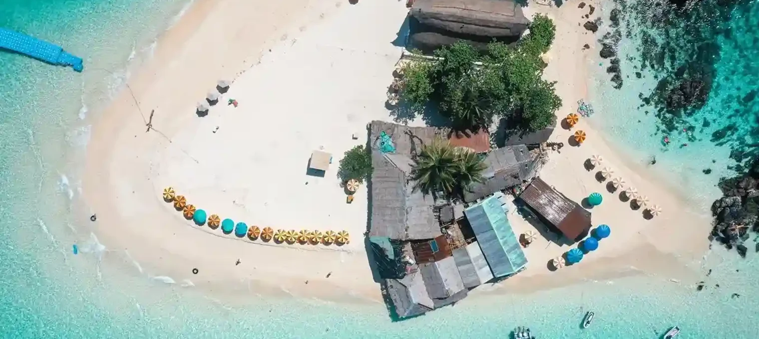 Aerial view of a tranquil beach in Phuket with colorful umbrellas and clear blue waters.