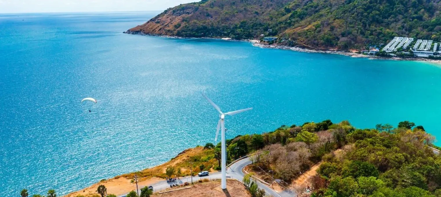 Вид на побережье Пхукета с ветряной турбиной и парапланеристом в воздухе.