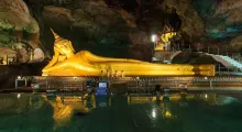 Reclining golden Buddha statue inside a cave temple in Phuket, Thailand.