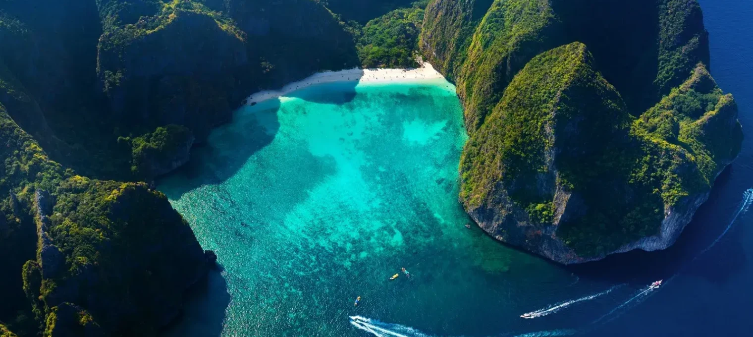 Aerial view of a stunning turquoise bay surrounded by lush green cliffs in Phuket.