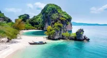 Stunning tropical beach in Phuket with turquoise waters and lush green cliffs.
