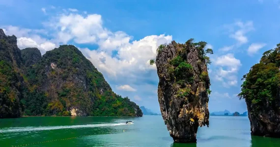Scenic view of limestone cliffs and a small boat near a rocky outcrop in Phuket.