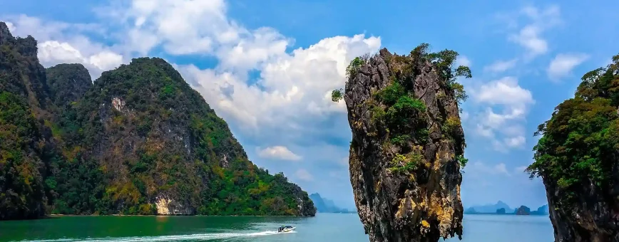 Scenic view of limestone cliffs and a small boat near a rocky outcrop in Phuket.