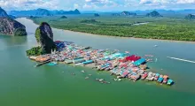 Aerial view of colorful floating village and lush green hills in Phuket, Thailand.