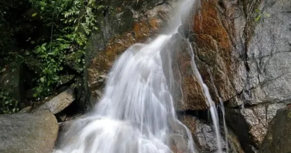 Водопад на фоне зеленых скал в Пхукете, Тайланд, стекает в мелкое озеро.