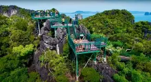 Suspended viewing platforms atop rocky cliffs in Phuket, surrounded by lush greenery and ocean views.