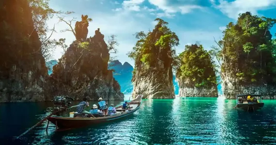 Scenic view of traditional boats near dramatic limestone cliffs in Phuket, Thailand.
