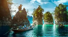 Scenic view of traditional boats near dramatic limestone cliffs in Phuket, Thailand.