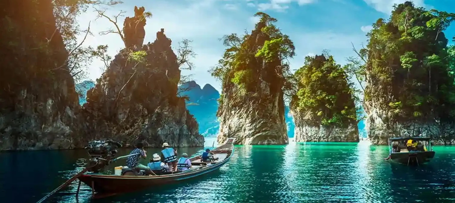 Scenic view of traditional boats near dramatic limestone cliffs in Phuket, Thailand.