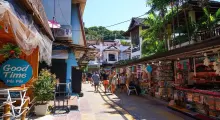 Colorful street market in Phuket, Thailand, with shops and tourists enjoying the day.