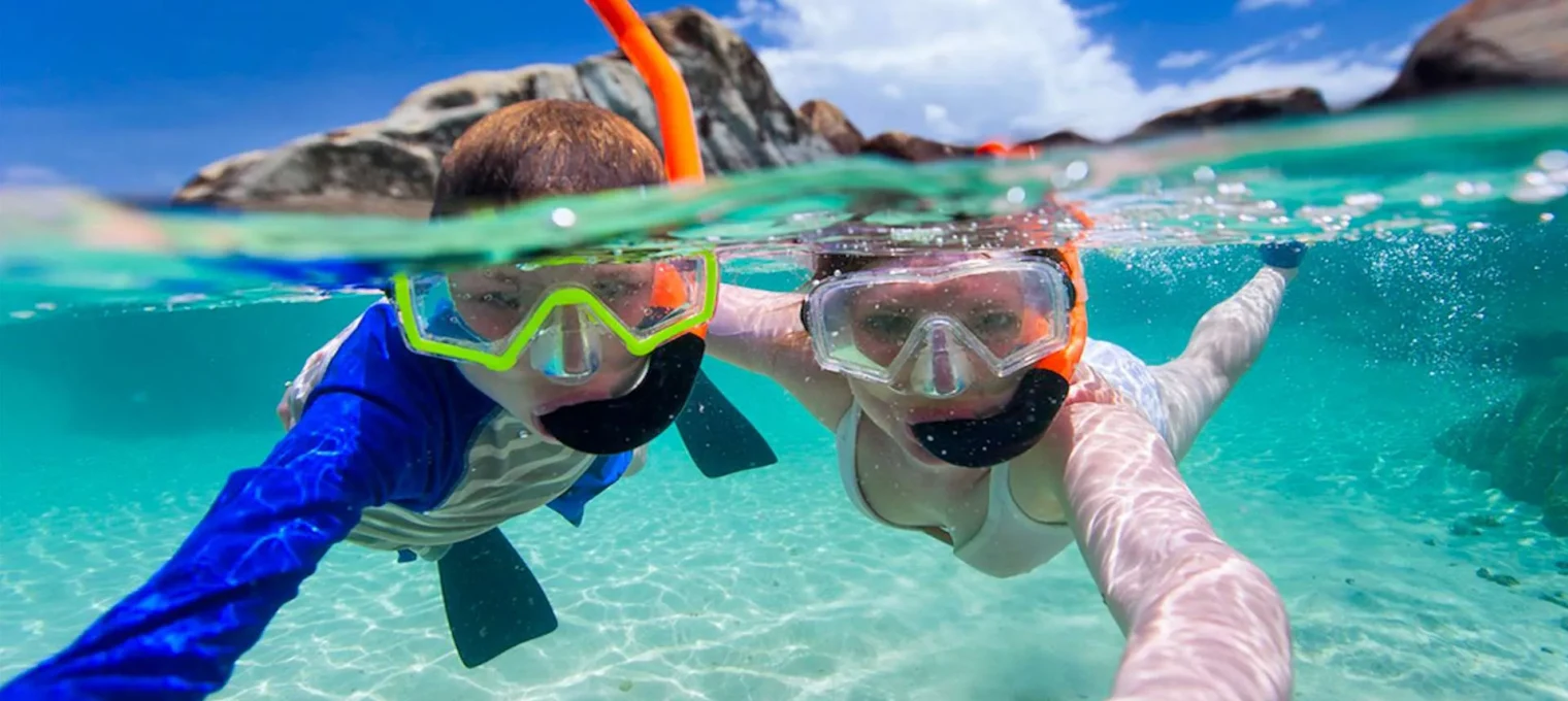 Two snorkelers explore clear turquoise waters in Phuket, enjoying underwater visibility.