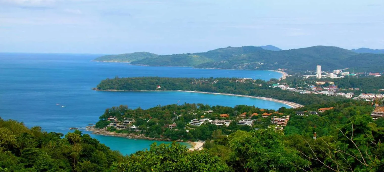 Scenic view of Phuket coastline with lush greenery and clear blue waters.