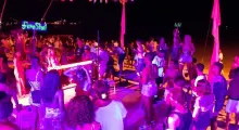 Crowd enjoying a lively beach party in Phuket with colorful lights at night.
