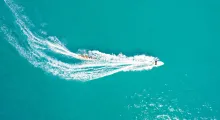 Aerial view of a jet ski and a colorful boat cutting through turquoise waters in Phuket.