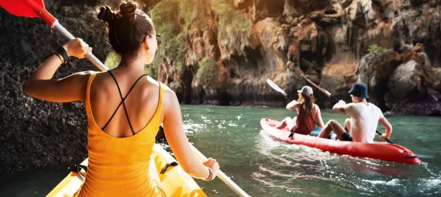 Kayakers explore the scenic waters of Phuket, surrounded by rocky cliffs and vibrant greenery.