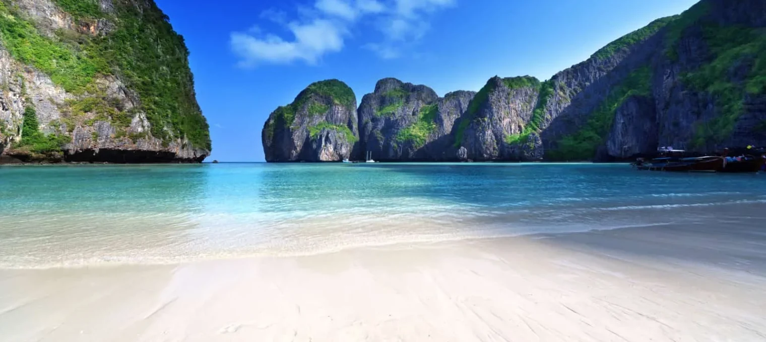 Turquoise waters and lush cliffs at a serene beach in Phuket, Thailand.