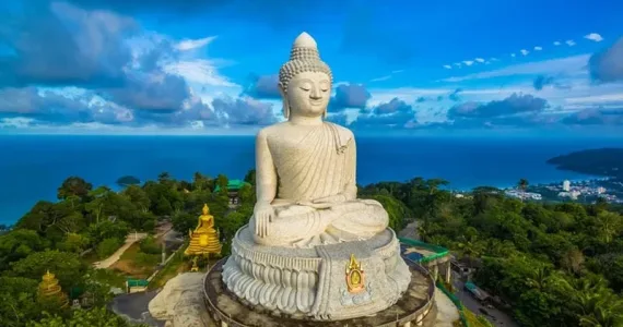 Большая статуя Будды на острове Пхукет, окруженная зеленью и морем.