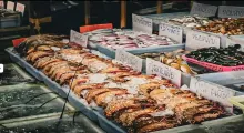 Fresh seafood display at a market in Phuket with various fishes and shellfish on ice.