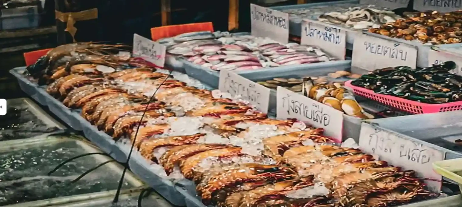Fresh seafood display at a market in Phuket with various fishes and shellfish on ice.