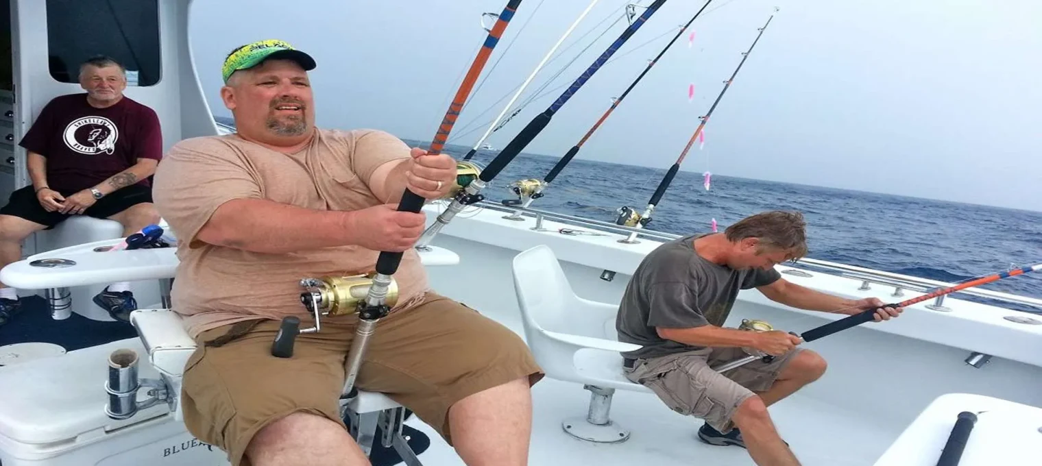Three men fishing on a boat in Phuket, with rods set up for deep-sea fishing.