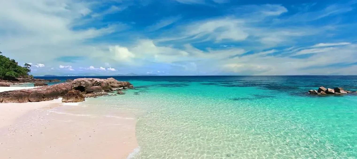 Stunning view of a turquoise beach in Phuket, with clear waters and a blue sky.
