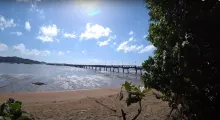 Scenic view of a beach in Phuket with a pier and clear blue skies.