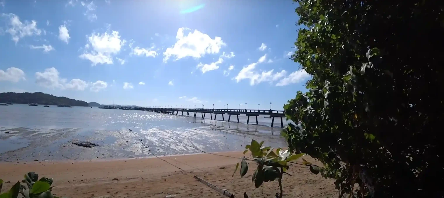 Scenic view of a beach in Phuket with a pier and clear blue skies.