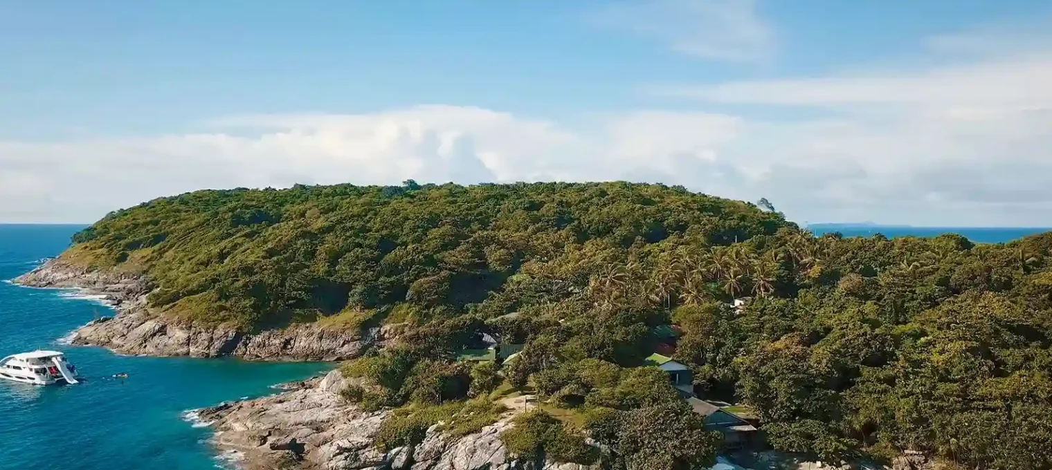 Aerial view of a lush green island with rocky shores in Phuket, Thailand.