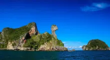 Phuket's limestone rock formation against a clear blue sky and calm waters.