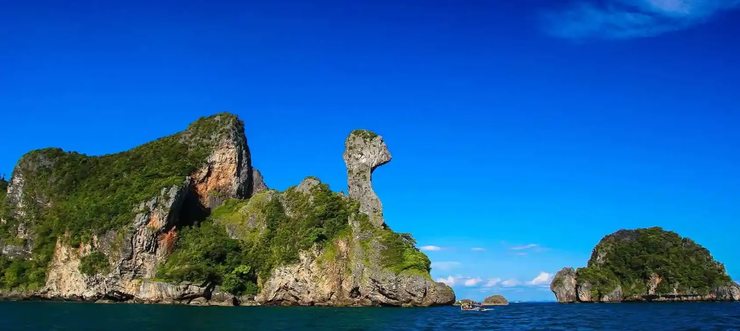 Phuket's limestone rock formation against a clear blue sky and calm waters.
