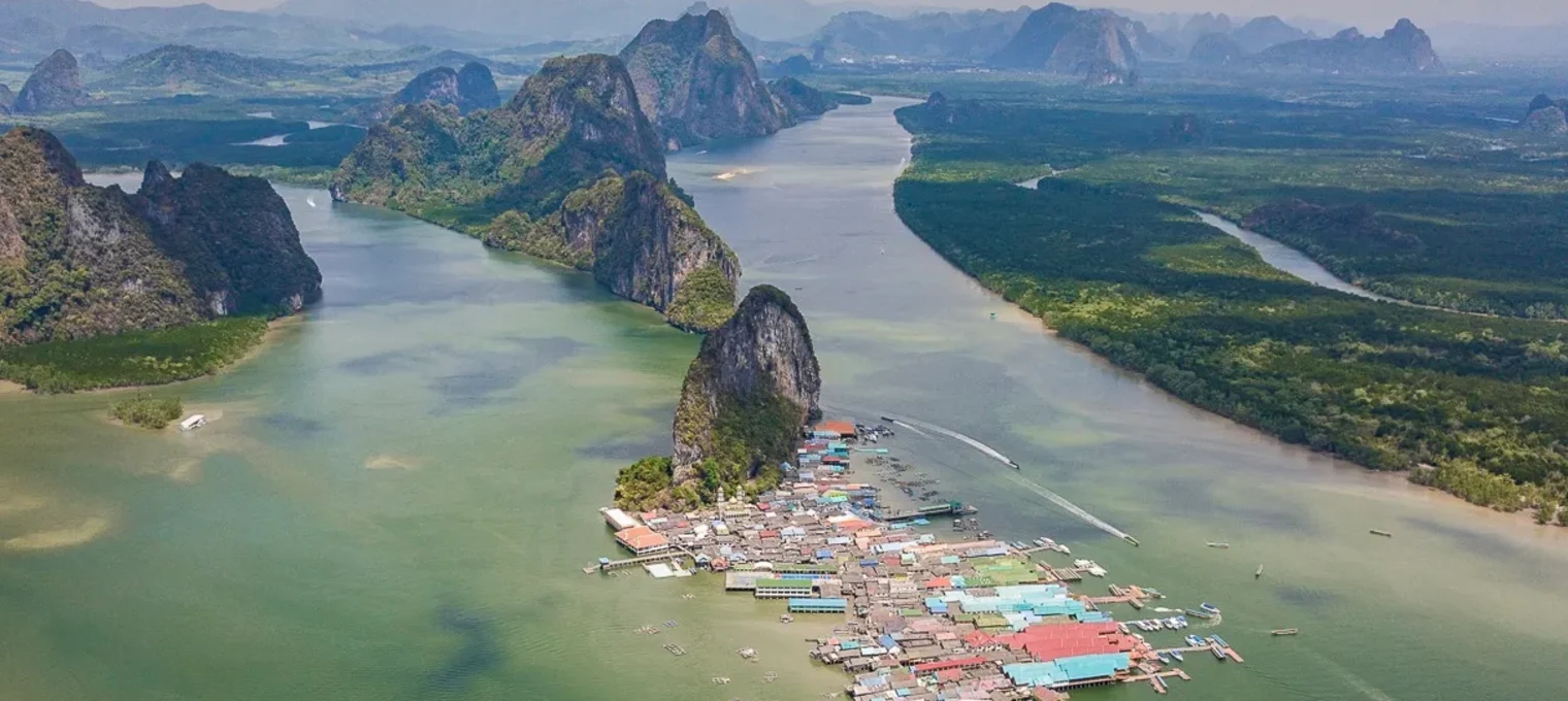 Aerial view of a floating village surrounded by lush mountains and serene waters in Phuket.