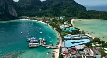Aerial view of Phuket's coastline with boats, lush hills, and sandy beaches.