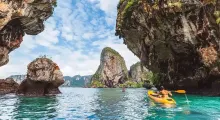 Kayakers explore rock formations and clear waters in Phuket's stunning landscape.