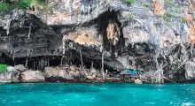 Rocky coastline near a cave with turquoise water in Phuket, Thailand. 