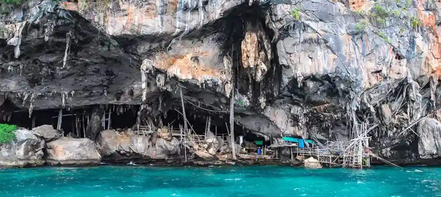 Rocky coastline near a cave with turquoise water in Phuket, Thailand. 