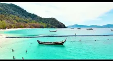 A serene beach scene in Phuket with turquoise waters and traditional boats.
